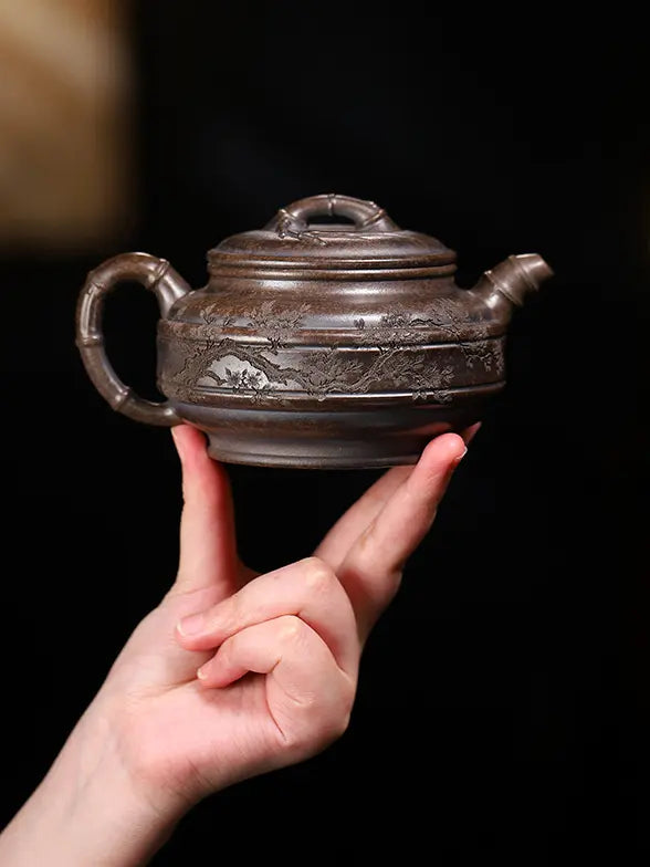 Hand holding a deep bronze-brown bamboo drum zisha teapot to show its scale