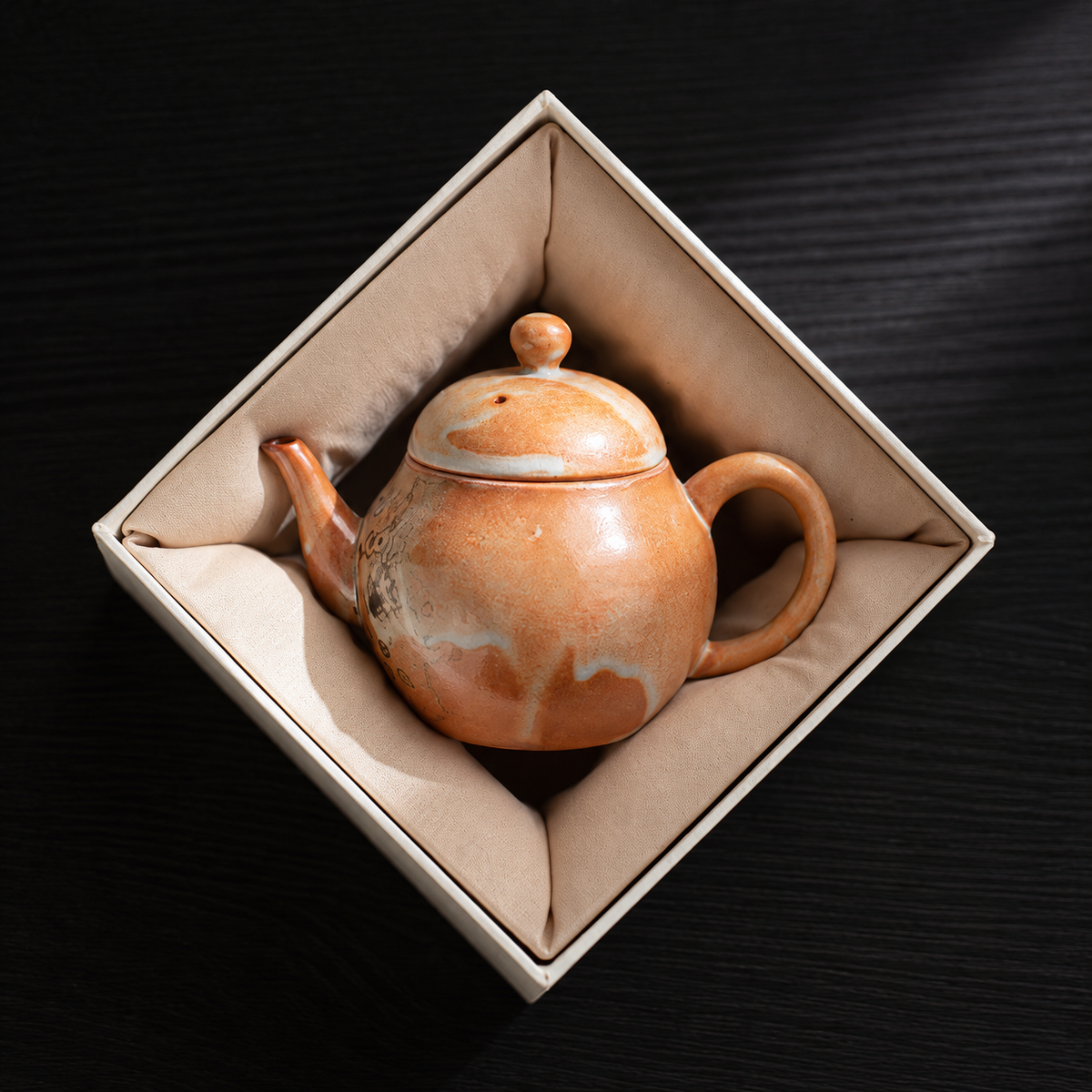 Liting ceramic teapot resting inside a padded gift box