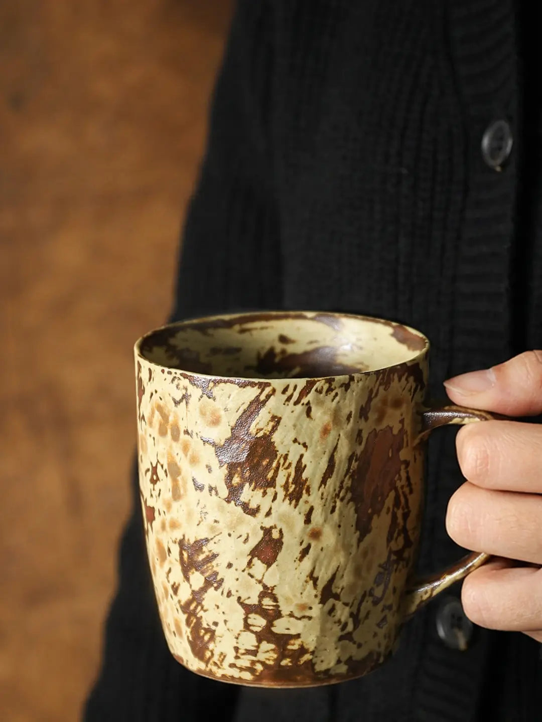 Hand holding a Mango Yellow reactive glaze ceramic coffee mug with a rounded handle
