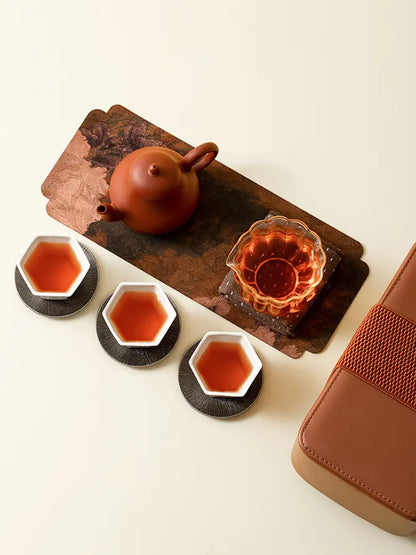 Overhead view of a portable gongfu tea set with three ceramic cups and glass pitcher
