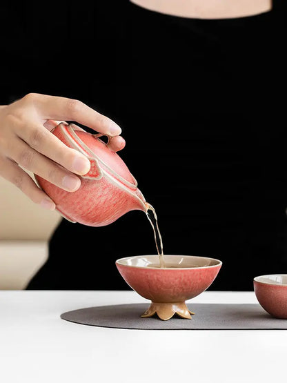 Tea being poured from the coral pomegranate teapot into the flower-footed host cup
