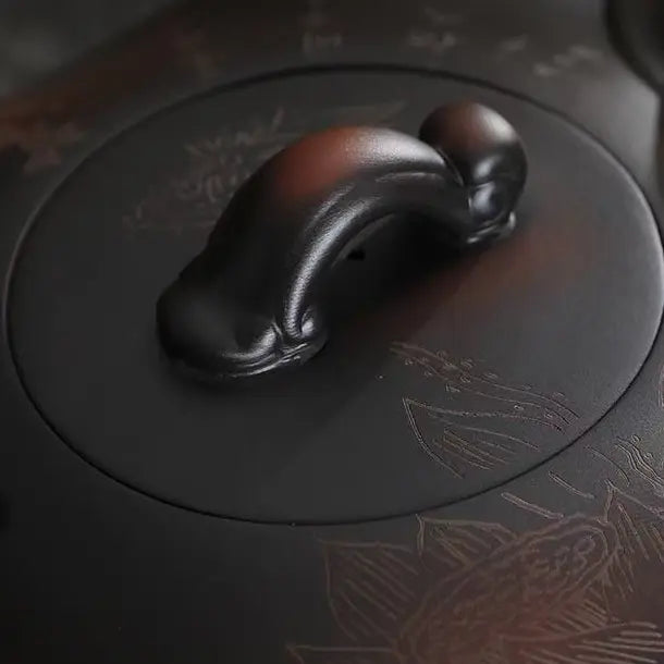 Close-up of the sculptural lid knob and carved surface of the Yixing zisha teapot
