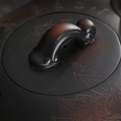 Close-up of the sculptural lid knob and carved surface of the Yixing zisha teapot