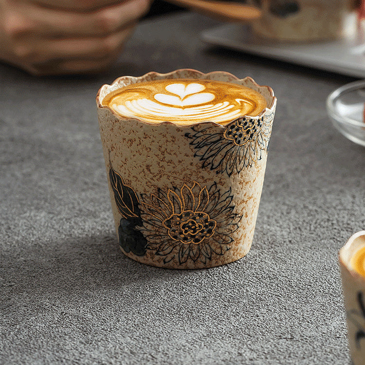 Sunflower-pattern ceramic coffee cup filled with latte art on a gray tabletop
