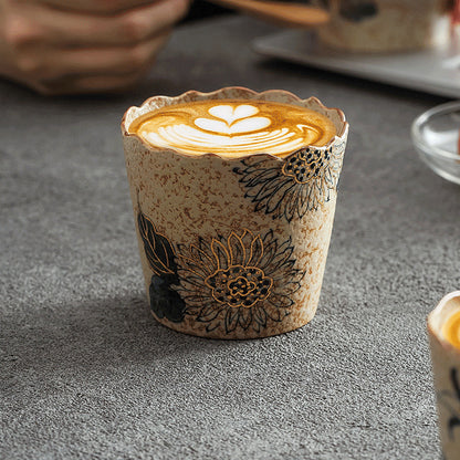 Sunflower-pattern ceramic coffee cup filled with latte art on a gray tabletop
