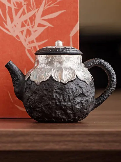 Black zisha lotus teapot photographed against a warm red studio background
