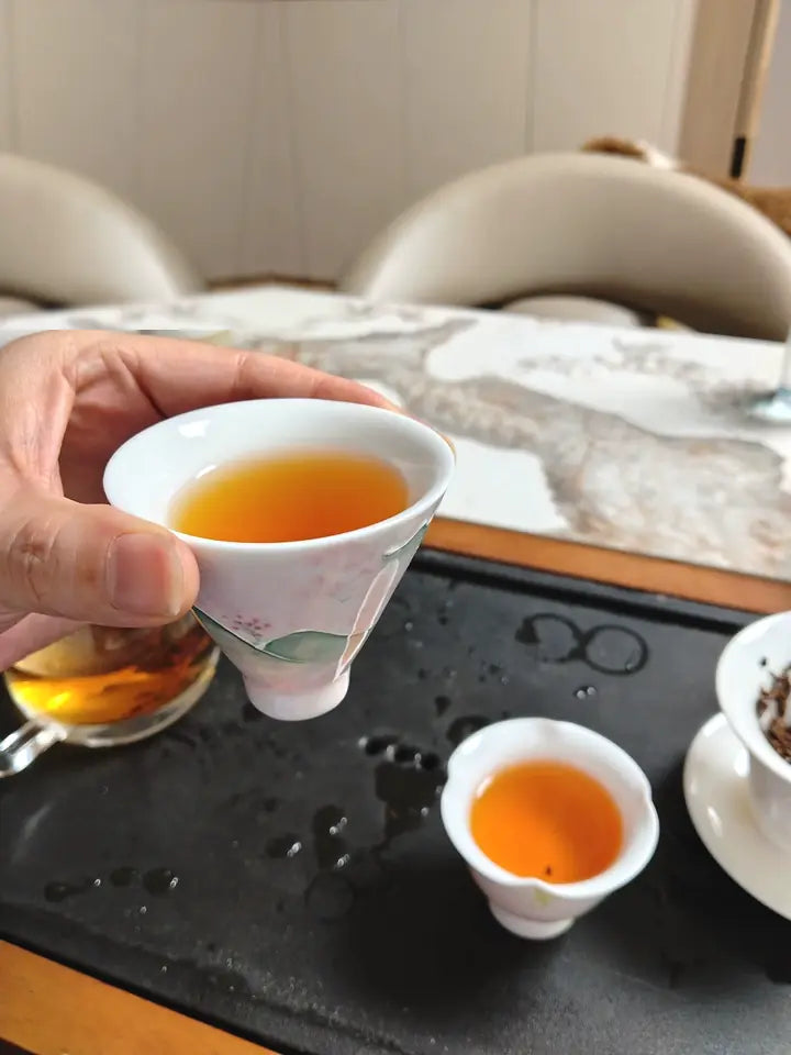 Pink-green landscape teacup filled with tea in a home gongfu tea setting