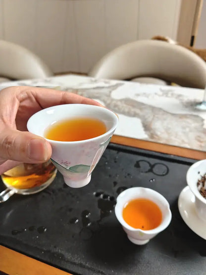 Pink-green landscape teacup filled with tea in a home gongfu tea setting