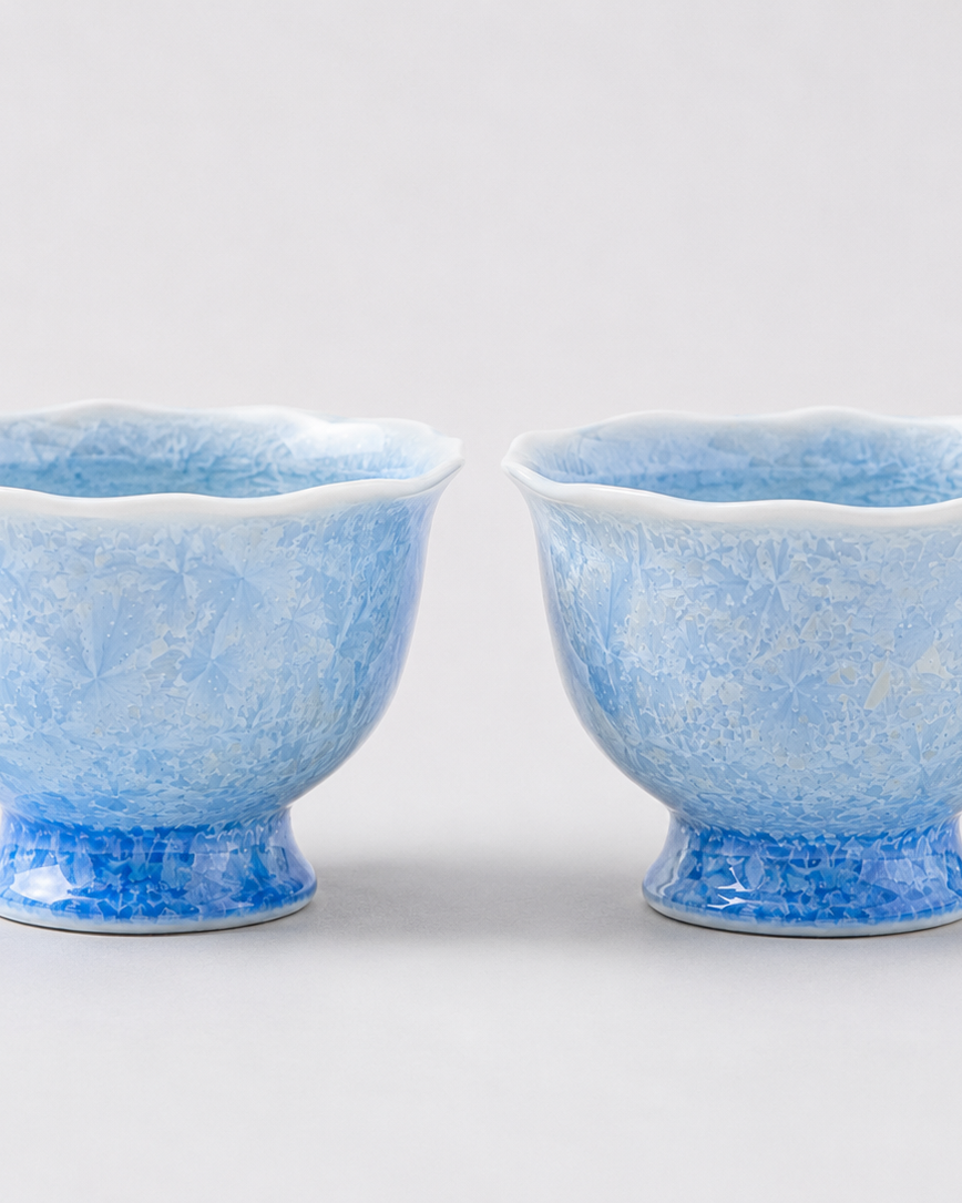 Two pale blue crystalline glaze cups showing natural variation in crystal patterns