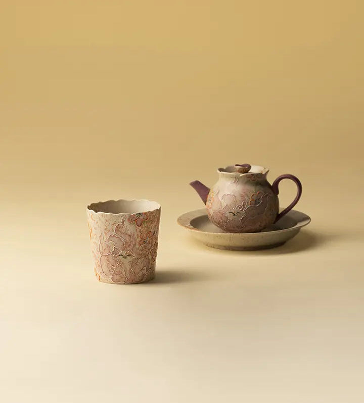 Nine-tailed fox ceramic coffee cup displayed beside a teapot and tray on a beige tabletop
