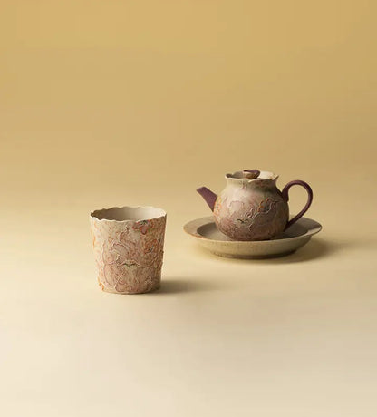 Nine-tailed fox ceramic coffee cup displayed beside a teapot and tray on a beige tabletop
