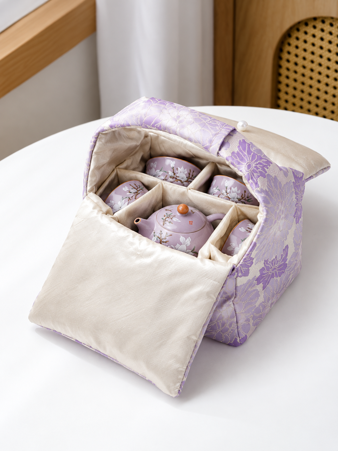 Purple floral travel bag opened to show the padded divided interior and stored tea set
