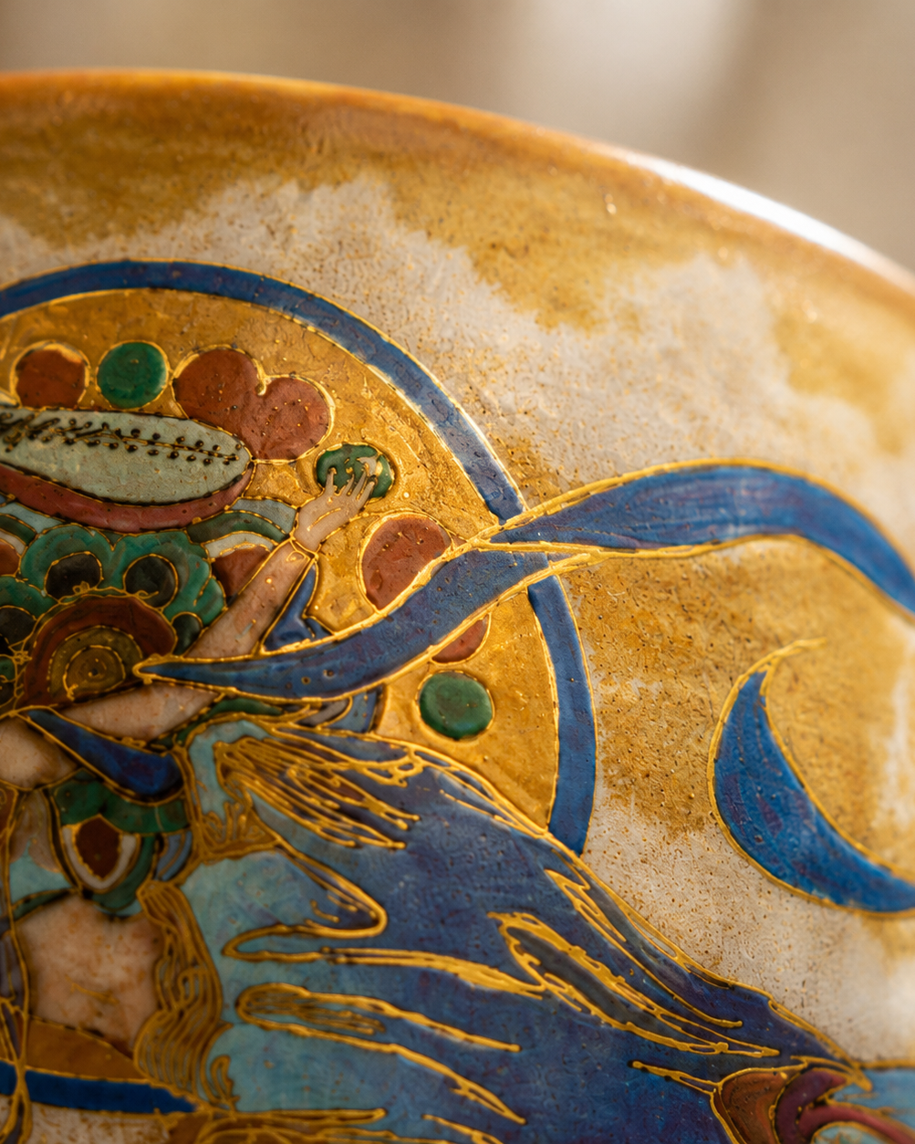 Close-up of gold-toned linework with blue-green and red-brown painted details