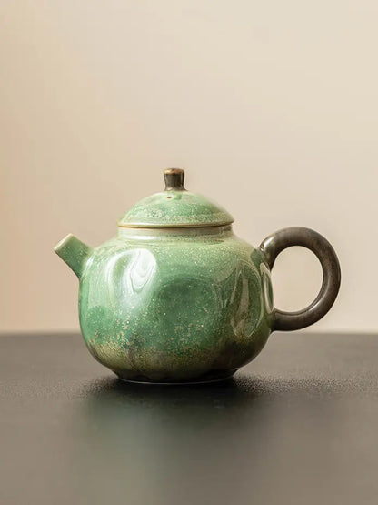 Front view of the green reactive-glaze ceramic teapot with a short straight spout
