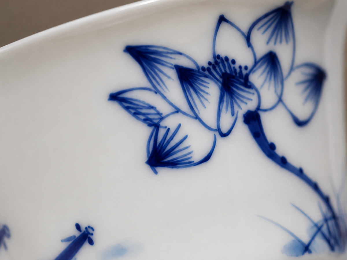 Close-up of hand-painted blue lotus brushwork on the white porcelain bowl