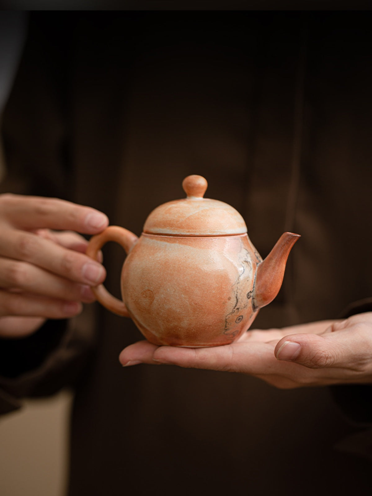 Compact Liting ceramic teapot held in two hands to show its scale