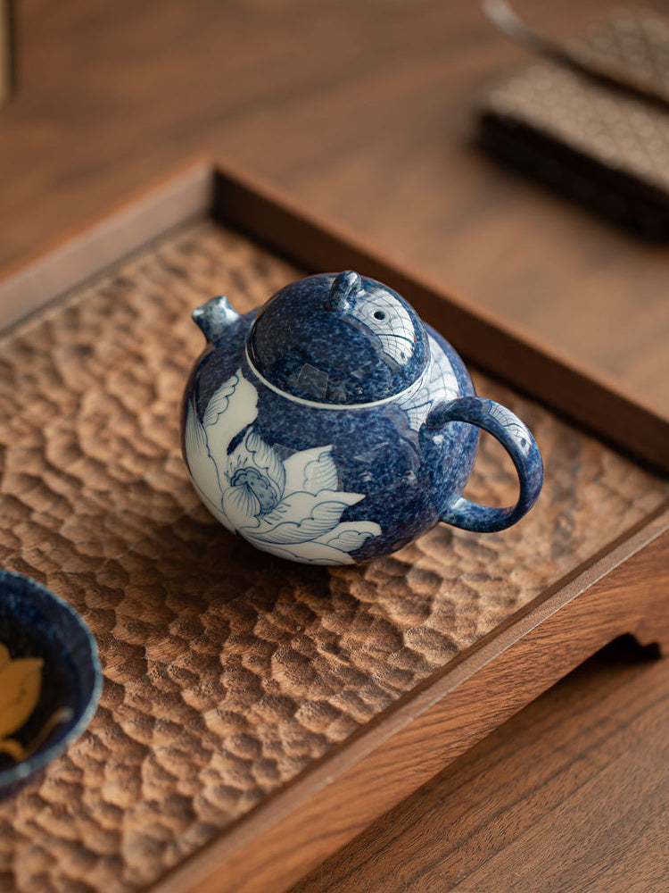 Top view of the lotus ceramic teapot on a textured wooden tray
