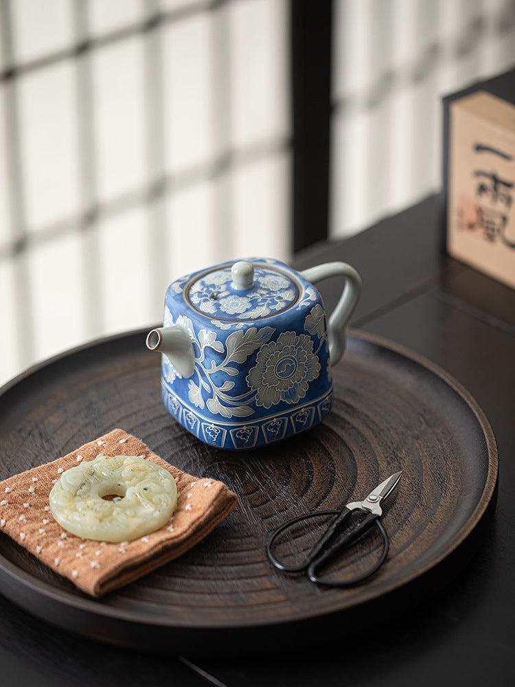 Overhead view of a blue peony ceramic teapot arranged on a round tea tray
