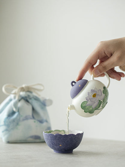 Hand-painted purple lotus travel teapot pouring tea into the matching flower-rim teacup