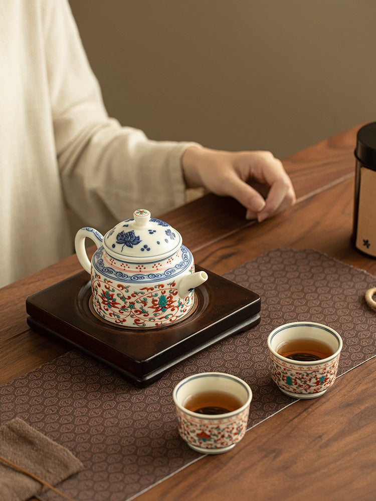 One lotus ceramic teapot and two matching cups in a warm home tea setting