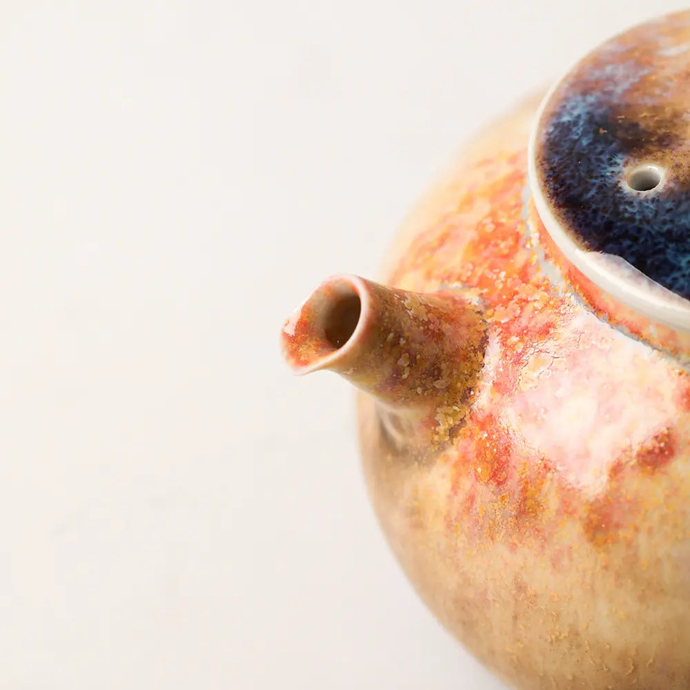 Close-up of the short teapot spout and layered amber, brown, and blue ash glaze