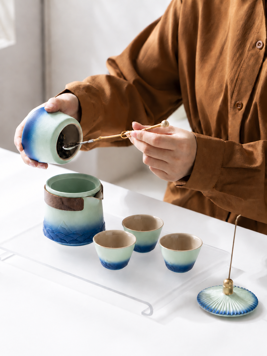 Preparing loose-leaf tea with a ceramic brewer and three matching cups
