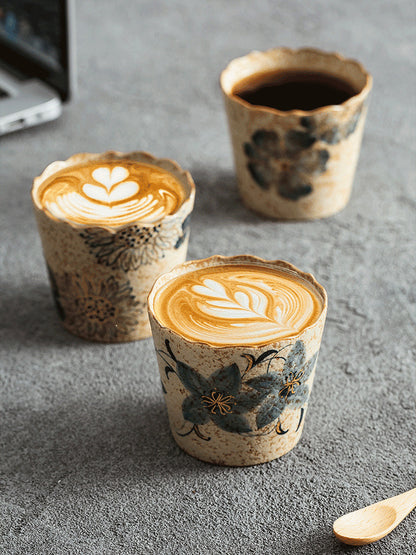 Three hand-painted scalloped ceramic coffee cups with latte and black coffee
