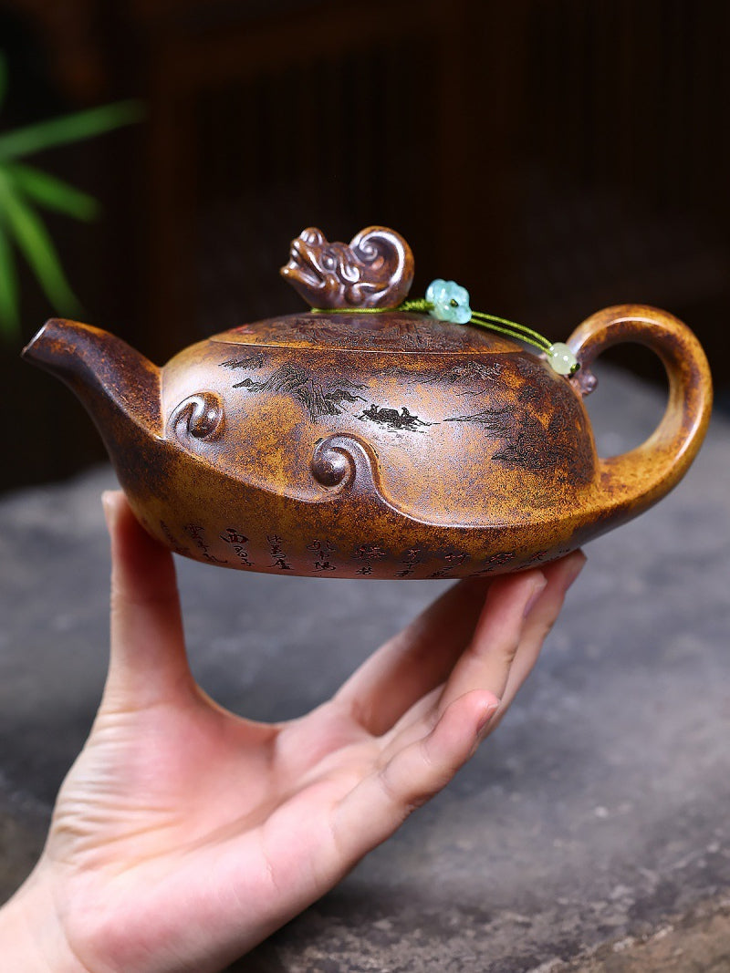 Hand holding the Yixing zisha wood-fired teapot to show its scale and rounded profile
