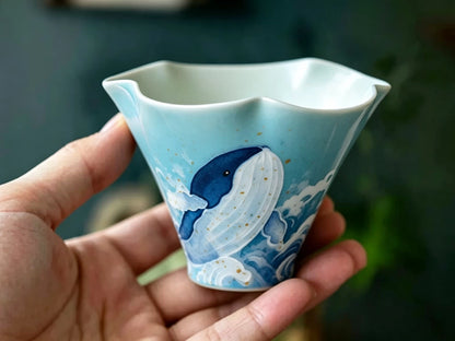 Close-up of the layered blue whale painting and gold-tone speckles on the ceramic cup