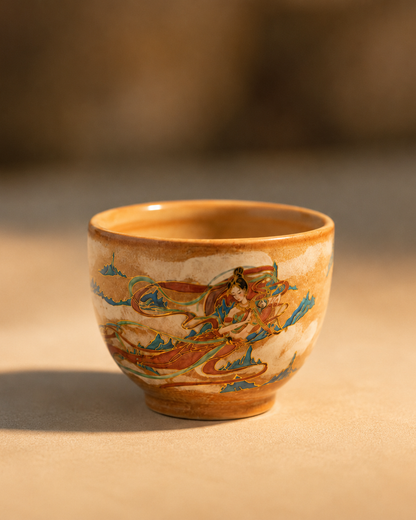 Dunhuang-inspired ceramic tea cup with gold-toned details catching natural sunlight