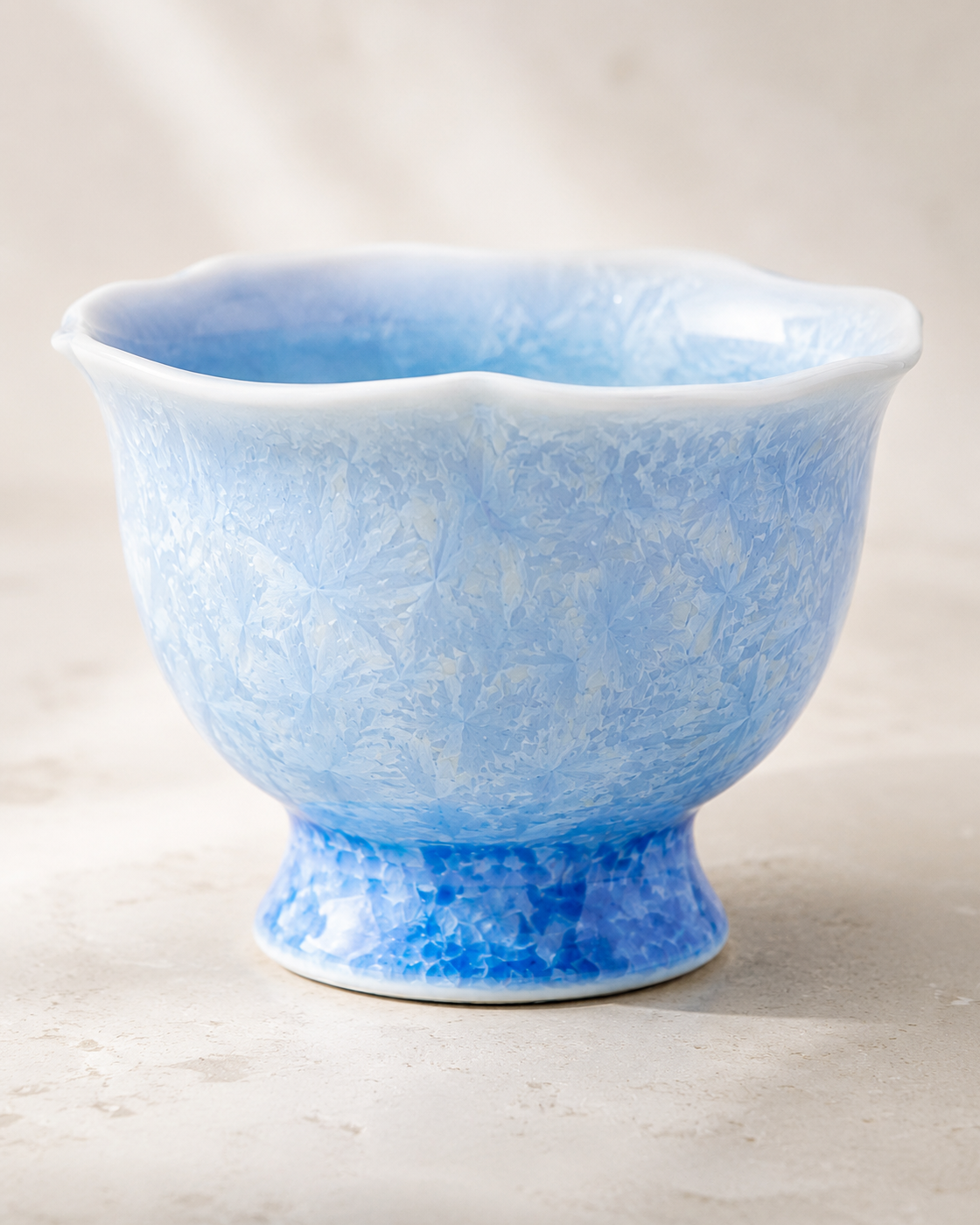 Pale blue flower-rim tea cup with crystalline glaze and a raised foot