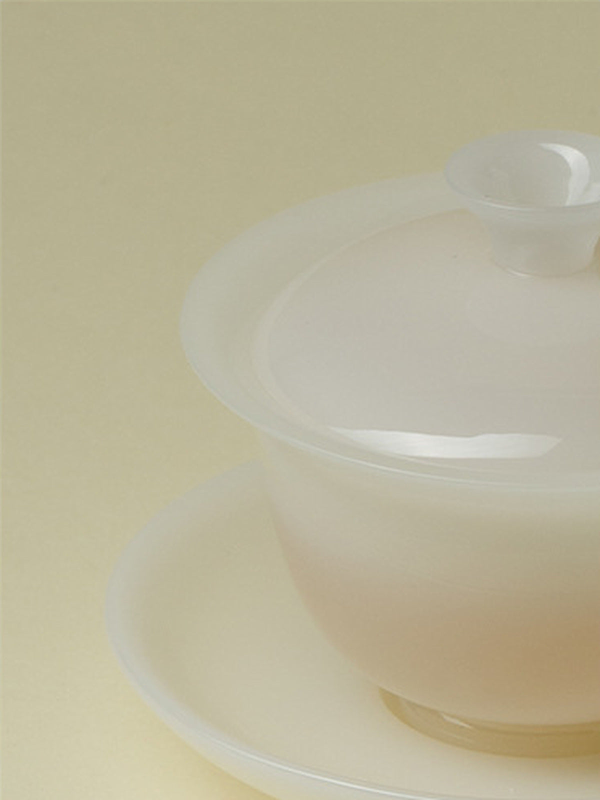 Close-up of a translucent white ceramic gaiwan with its matching saucer
