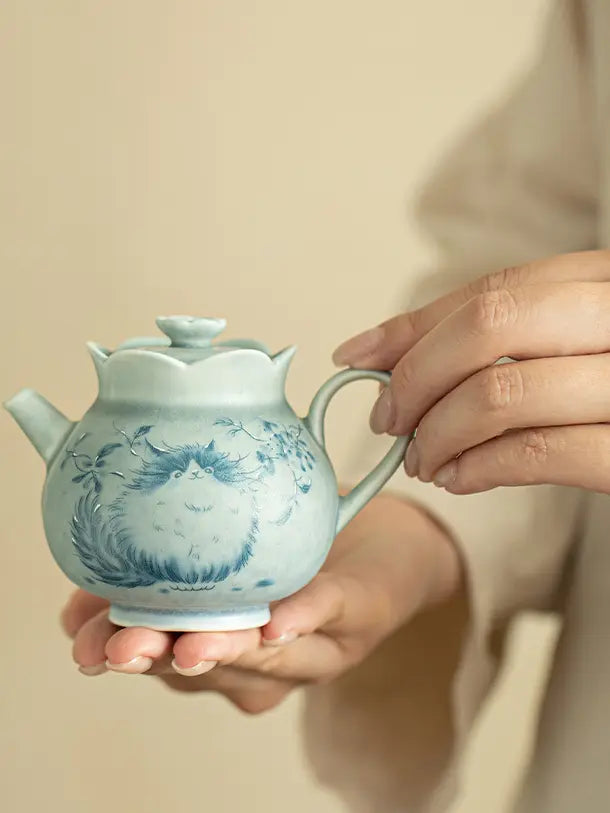 Person holding the compact Jingdezhen cat ceramic teapot to show its scale
