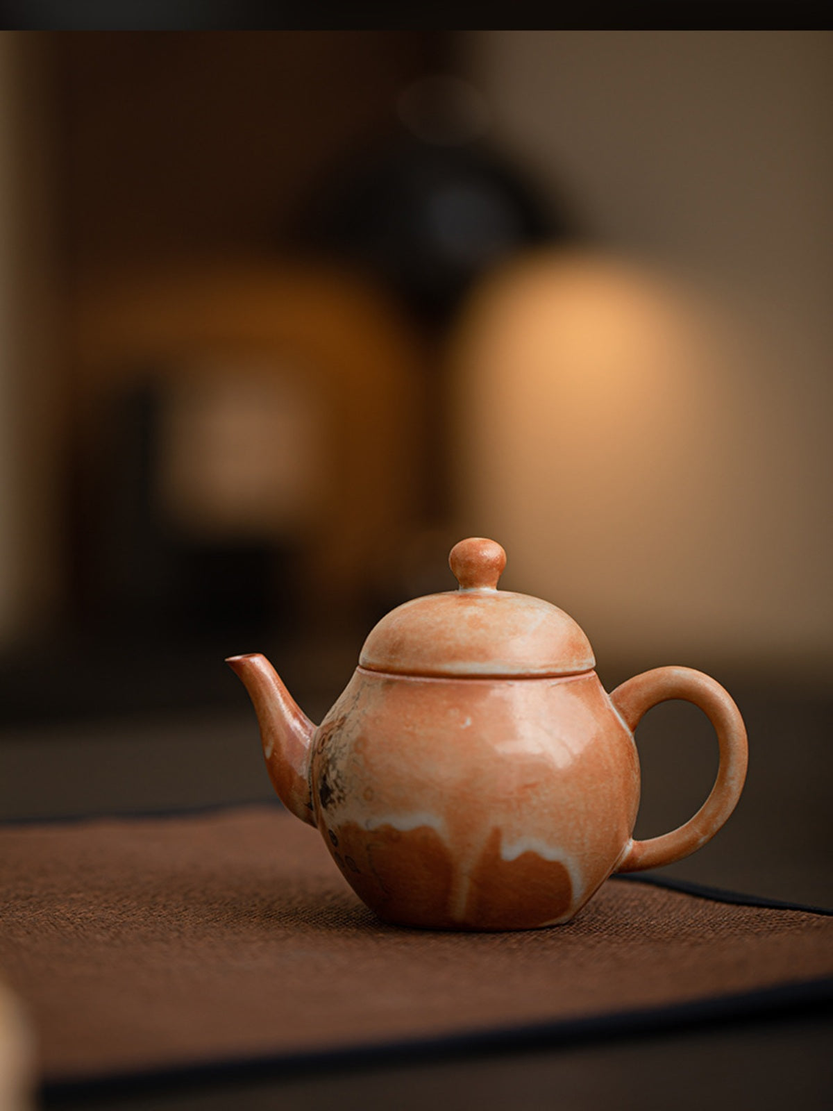 Liting kiln-glazed ceramic teapot on a tea mat in a warm interior