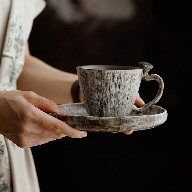 Hands presenting the handmade lotus pod coffee cup on its matching round plate