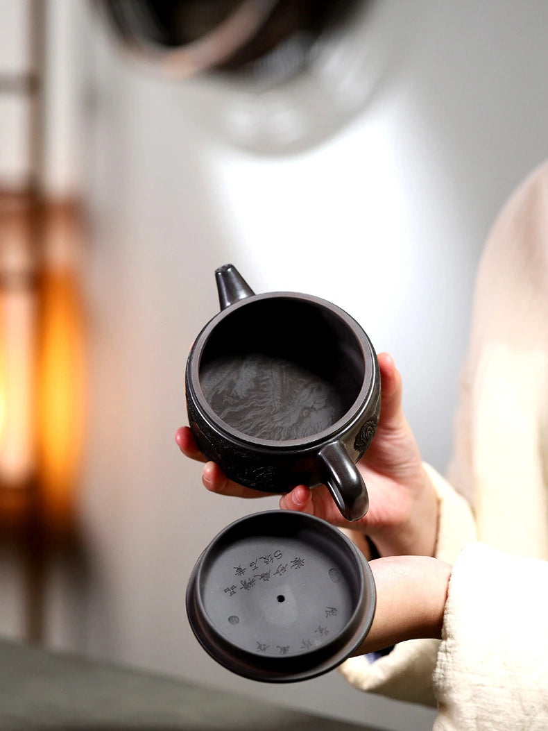 Open Yixing zisha teapot held with the lid below to show the interior and underside details