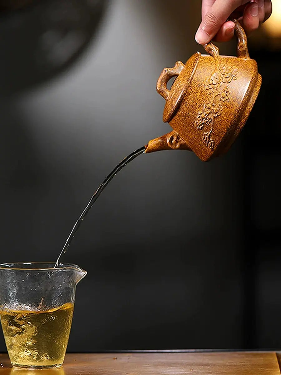 Golden-brown Shi Piao zisha teapot pouring tea into a glass pitcher