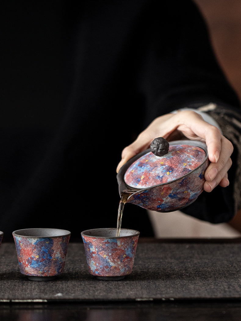 Galaxy glaze handleless ceramic teapot pouring tea into two cups
