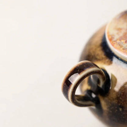 Close-up of the ceramic ring handle and dark brown wood-fired glaze detail