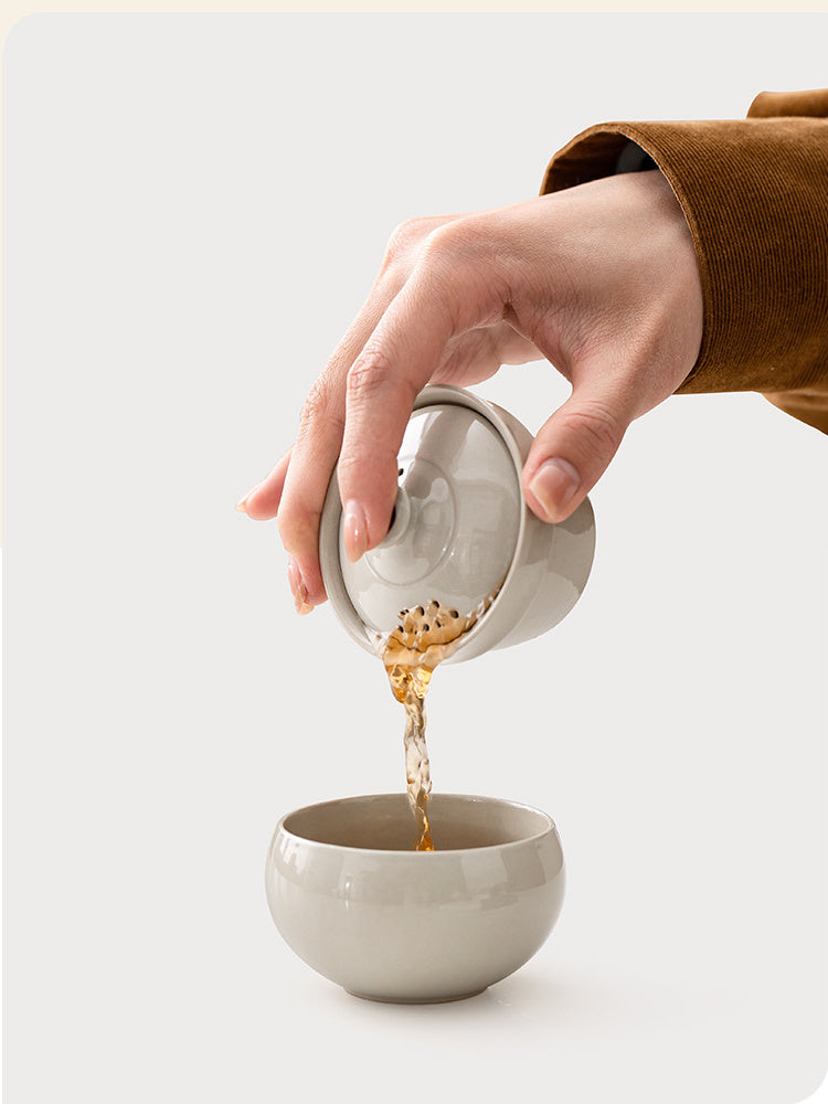 Tea pouring through the multi-hole lid filter from the ceramic brewer into the matching cup
