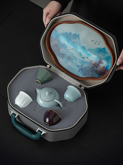 Open travel case holding a Xishi teapot and four kiln-inspired tasting cups beneath the landscape tray
