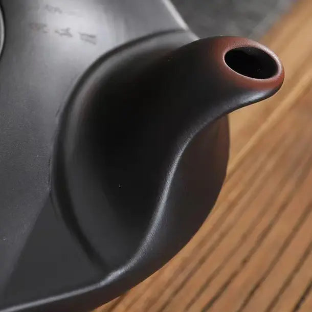Close-up of the elongated upturned spout on the dark brown Yixing zisha teapot