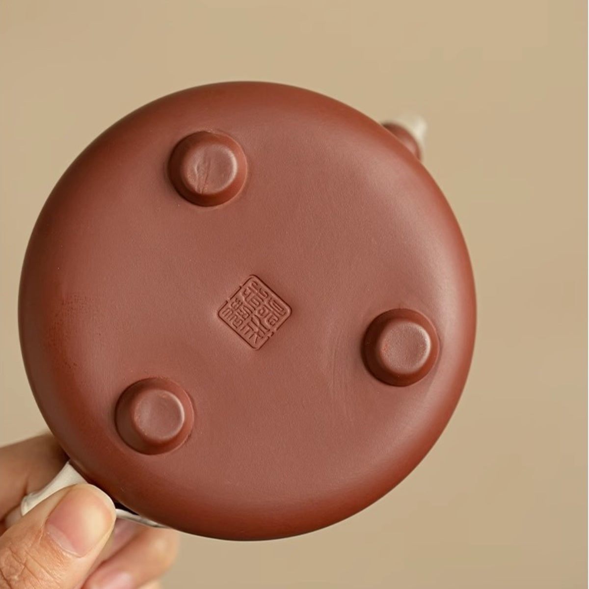 Bottom of the handmade Yixing zisha teapot showing three feet and a maker’s seal