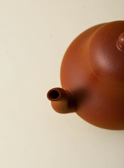 Close-up of the short spout on the reddish-brown zisha teapot
