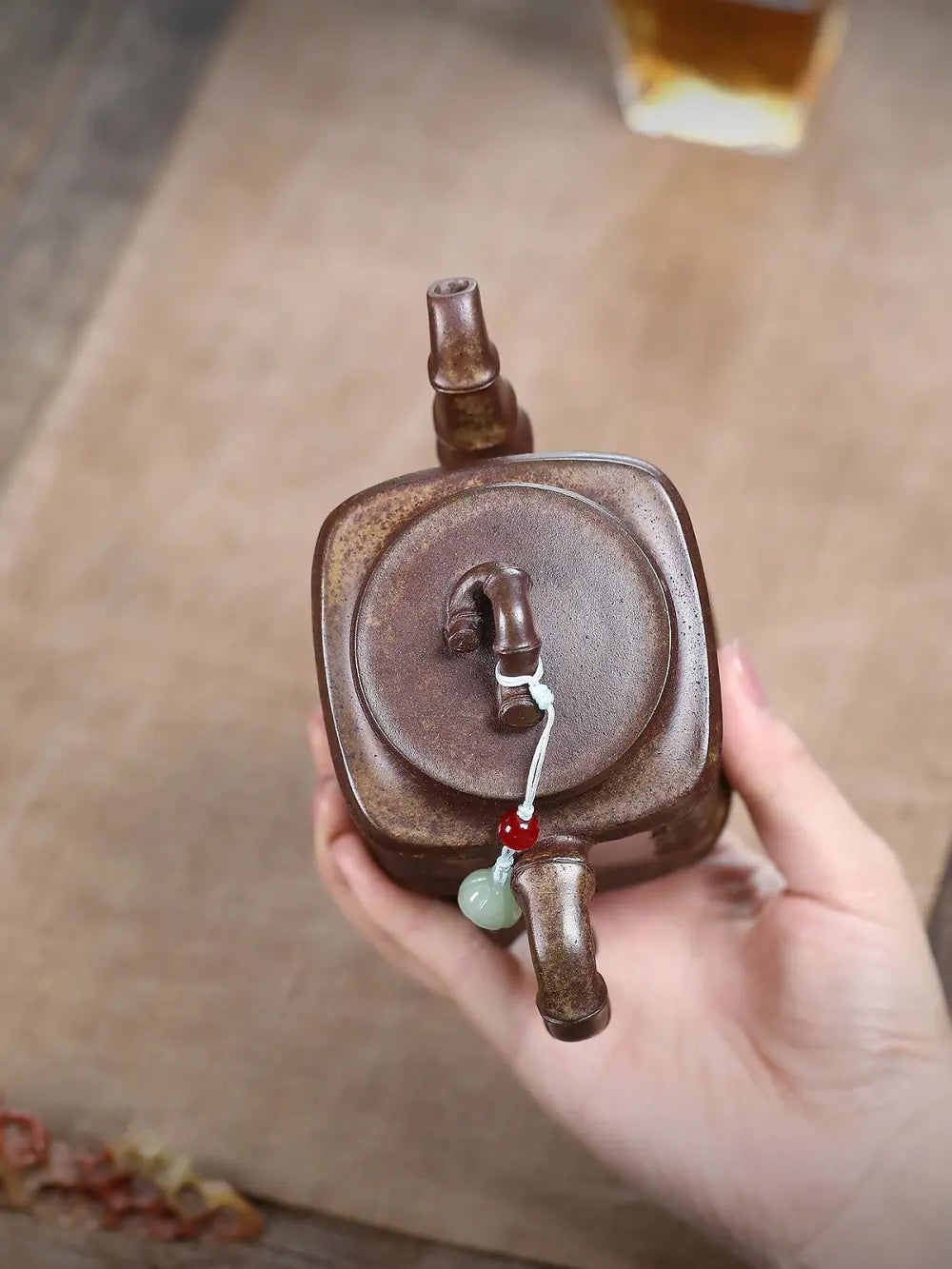 Top view of the square zisha teapot lid, bamboo-form knob, and red and pale green lid ornament
