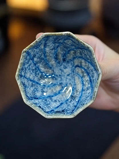 Close-up of the polygonal rim and blue-and-white glaze inside the handmade tea cup