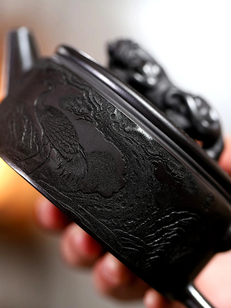 Close-up of crane and pine landscape carving on the side of the dark zisha teapot