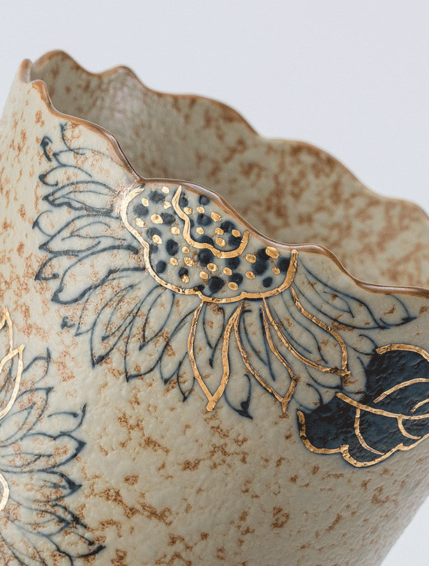 Close-up of hand-painted sunflower motifs and gold-toned details along the scalloped rim
