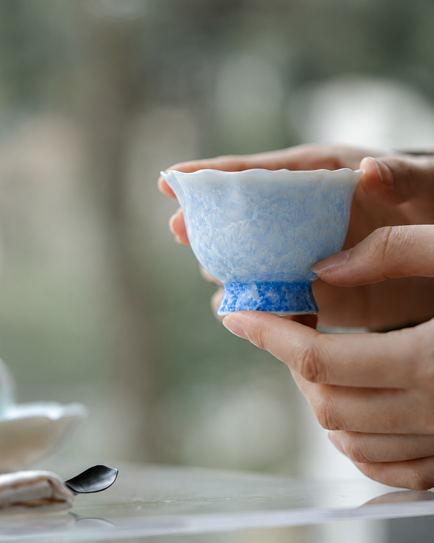 Hand holding an 80 ml pale blue crystalline glaze gongfu tea cup