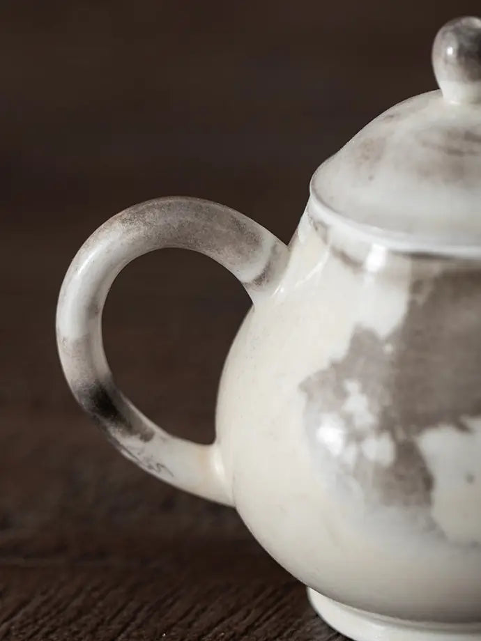 Close-up of the rounded teapot handle and natural ink-wash glaze variation